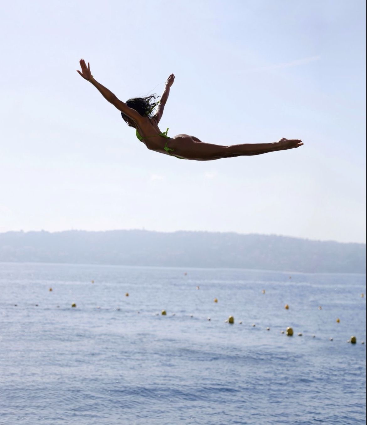 Woman diving through bright summer air above the sea