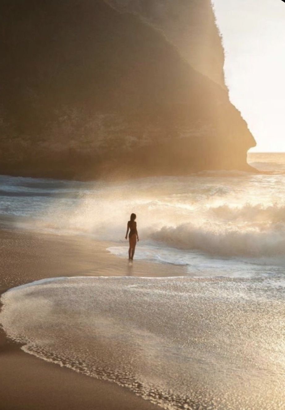 Woman walking alone along a golden beach