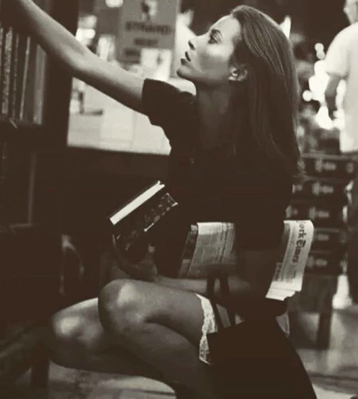 Woman reaching for a book in a softly lit bookshop