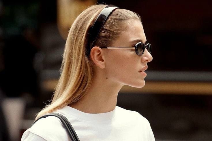 Woman in sunglasses and a headband seen in profile