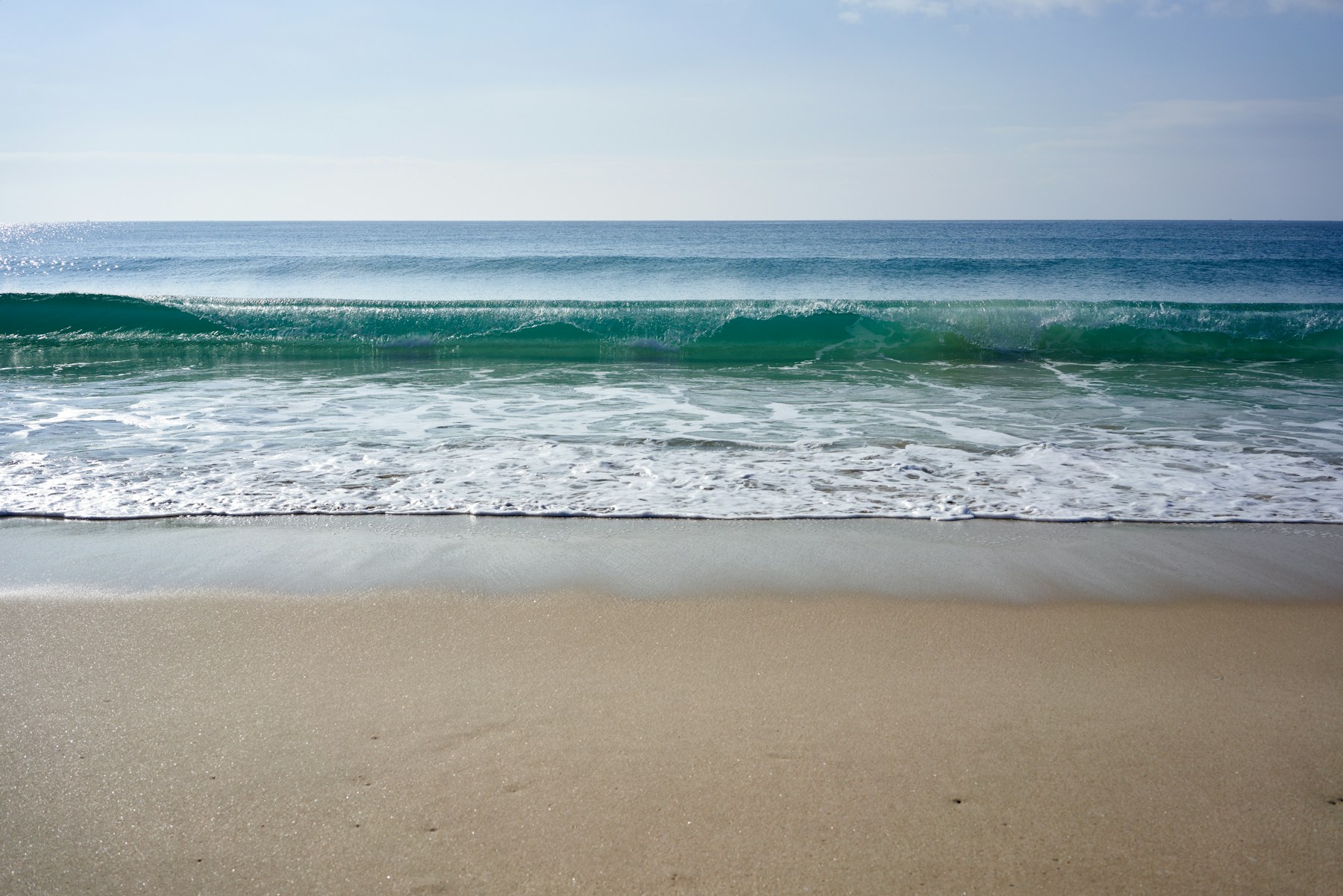 A clean Atlantic wave arriving on a wide beach